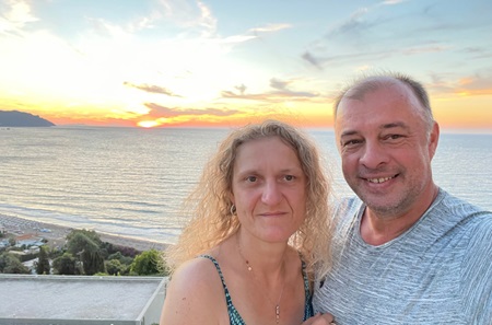 Woman and man smiling with sunset and water in the background 